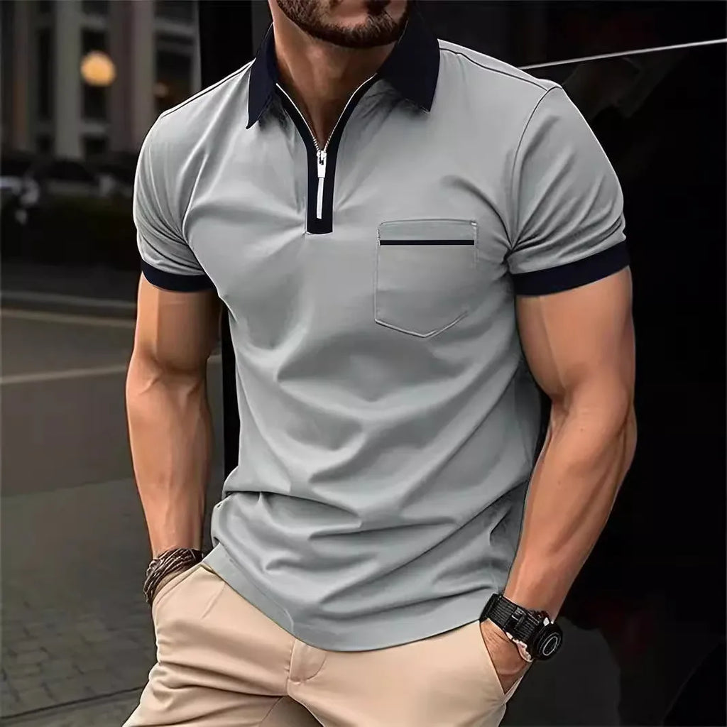 Man wearing a grey and navy blue casual t-shirt with a chest pocket and silver zip decoration detail.