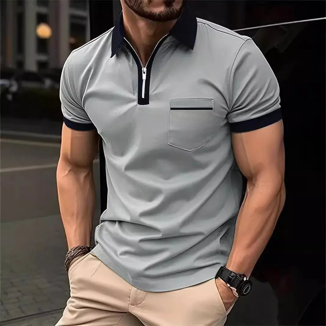 Man wearing a grey and navy blue casual t-shirt with a chest pocket and silver zip decoration detail.