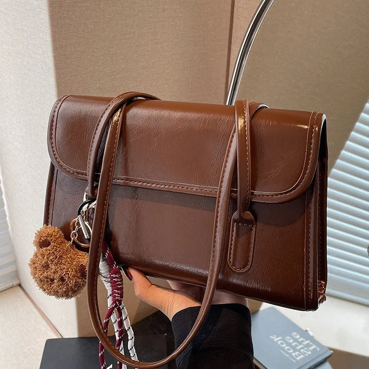 Brown women's PU leather shoulder bag with a square shape, double straps, and a detachable pendant.