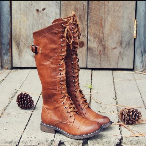 Women's black artificial PU knight boots with cross straps and buckle fastenings.
