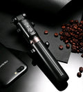 Black Bluetooth selfie stick tripod with extended rod, phone clamp, and deployed legs next to a smartphone