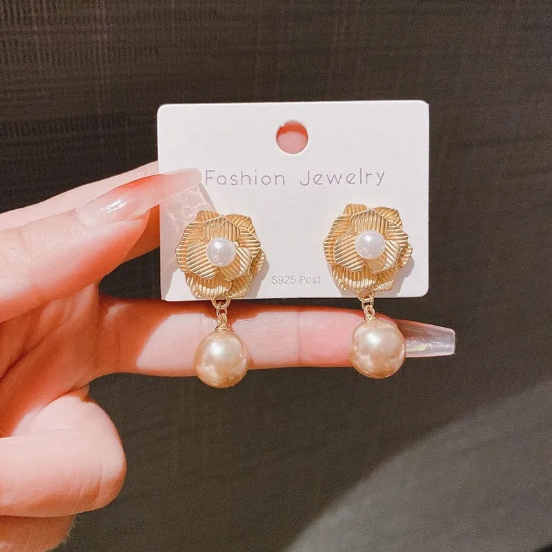 Gold flower stud earrings with a pearl, opal, and needle rose design on a white background.