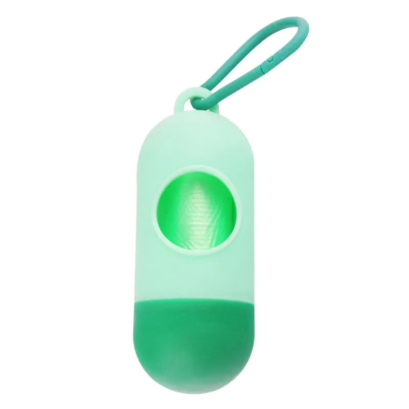 Compact black dog poop bag holder with hook and Velcro strap, shown attached to a pair of trousers.
