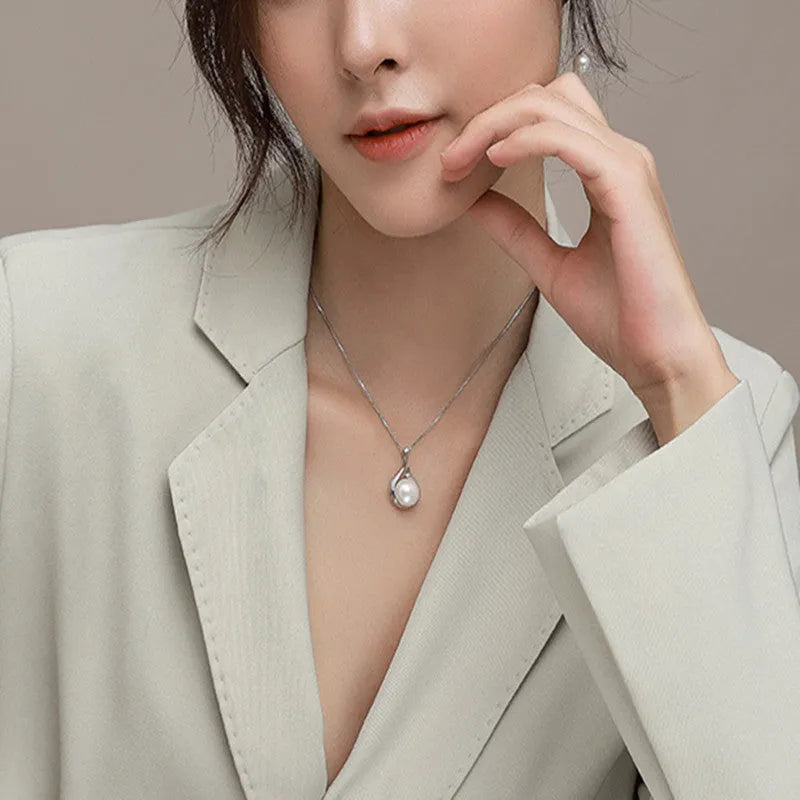 S925 silver necklace with natural freshwater pearl and geometric mother-of-pearl pendant on cross chain over a knitted sweater