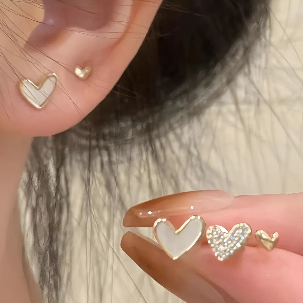 Set of three pairs of women's heart-shaped alloy drop earrings in gold, black, pink colours.