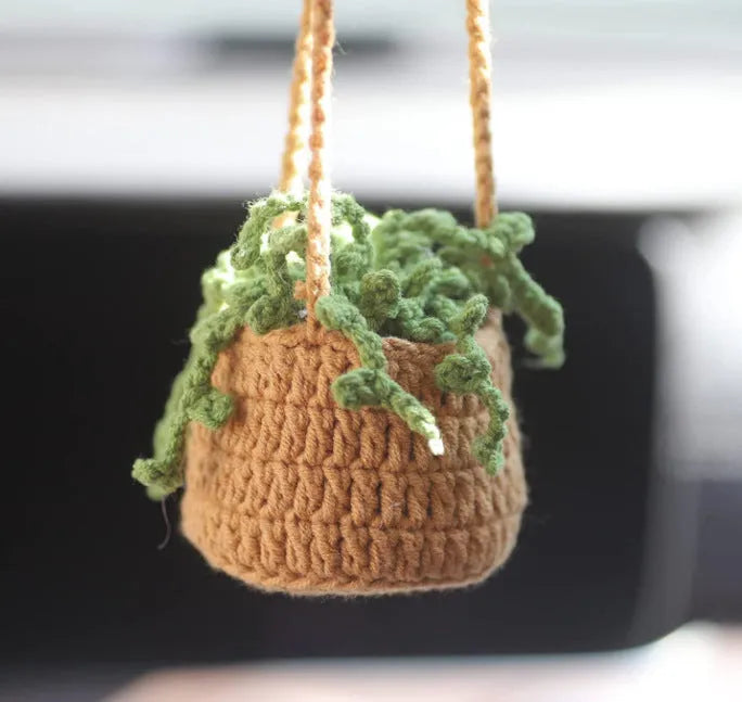 Green and white crochet wool car plant decoration with hanging rope on car dashboard