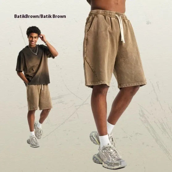 Man wearing loose fit batik washed cotton terry shorts with patch craft detailing in a street fashion style.