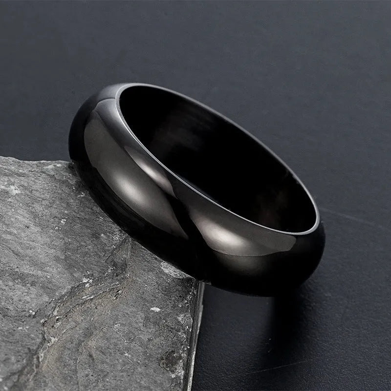 Glossy electroplated titanium steel ring in gold, black, and steel colours on a grey background.