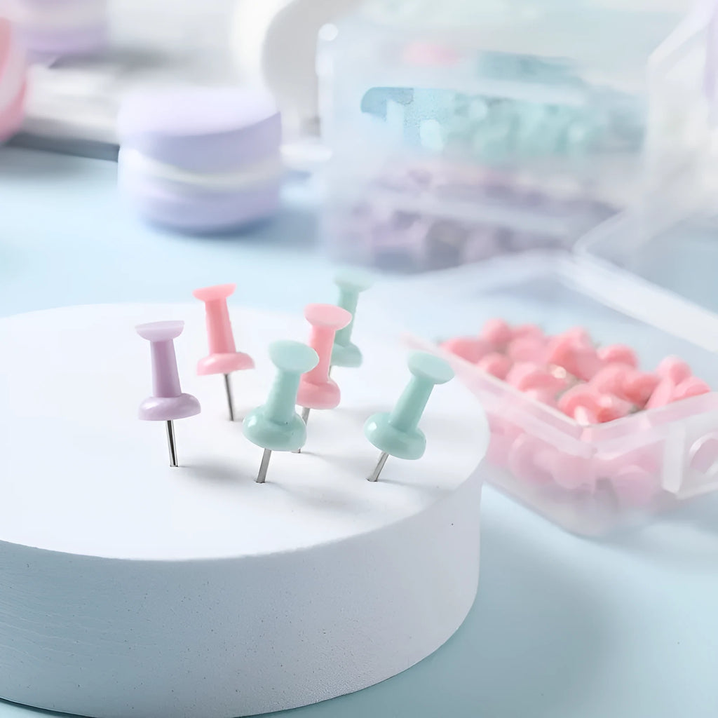 Plastic push pins in mint green, lavender, and pink, showing large and small sizes in a small box.