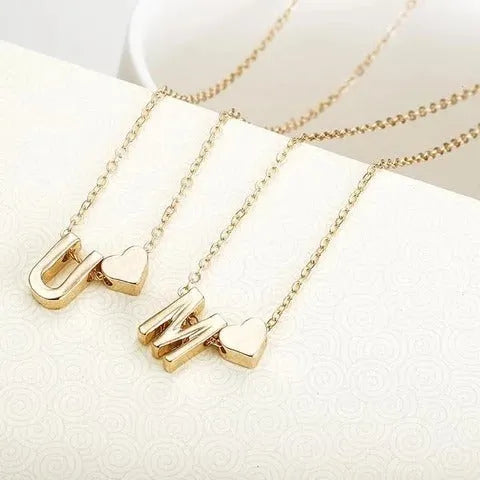 Gold alloy peach heart pendant with a letter charm on a chain.
