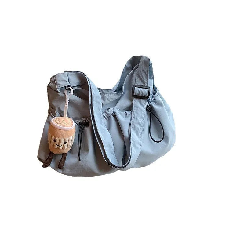 Green ultra-light pleated crossbody student bag showing folding design and split outer pocket
