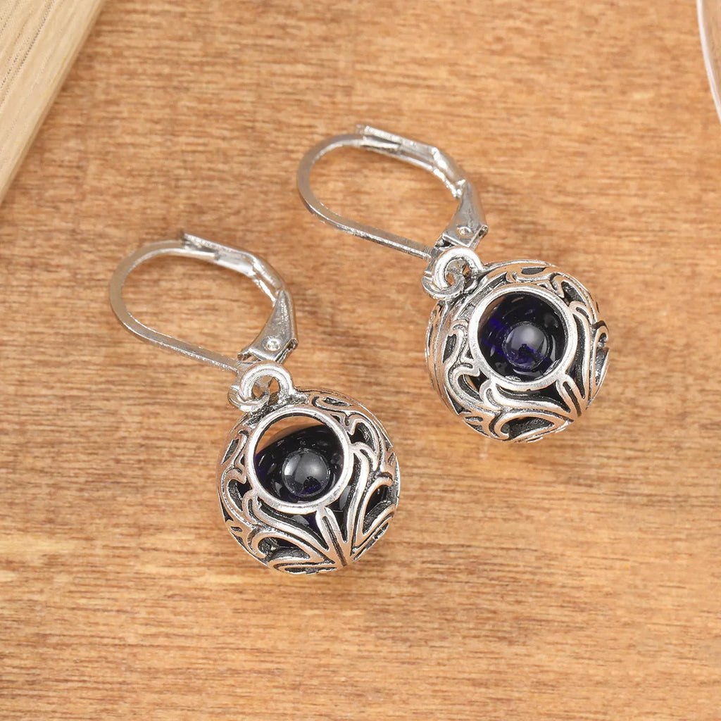 Silver tone pendant earrings with hollow geometric design, blue gemstones, and vintage engraving detail