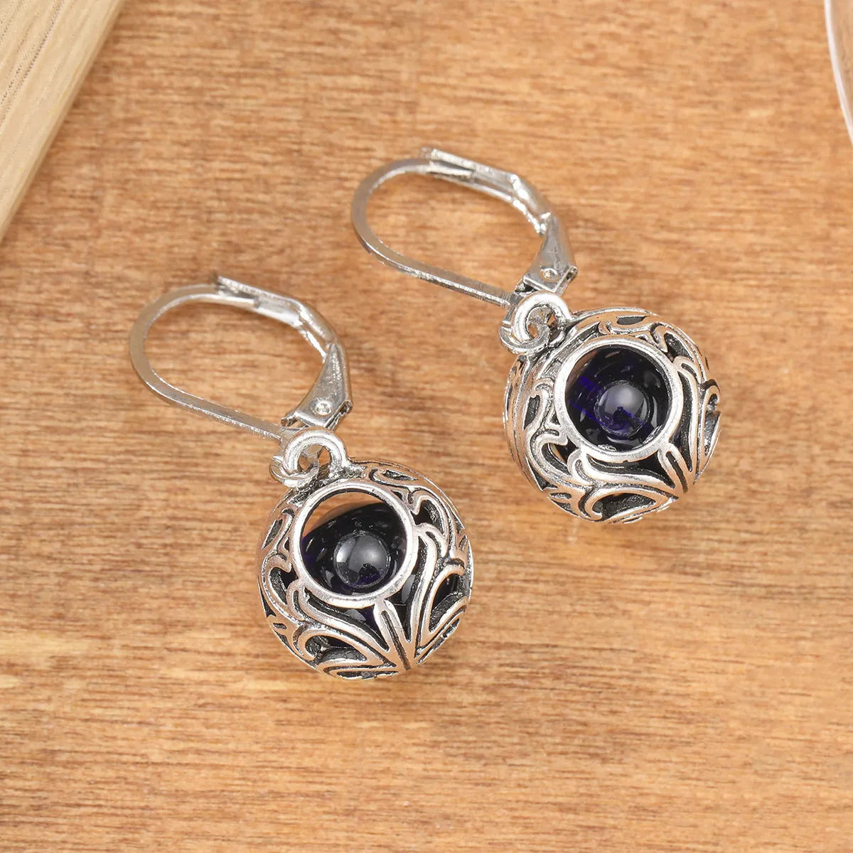 Silver tone pendant earrings with hollow geometric design, blue gemstones, and vintage engraving detail