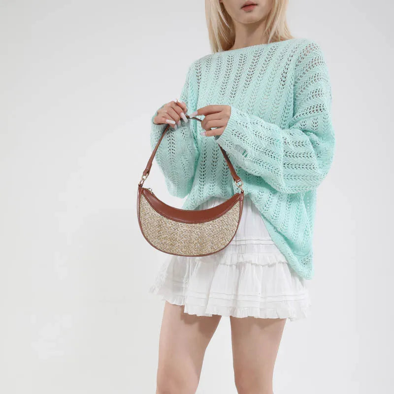 Hard structured straw dumpling shaped women's crossbody shoulder bag in black with contrast stitching.