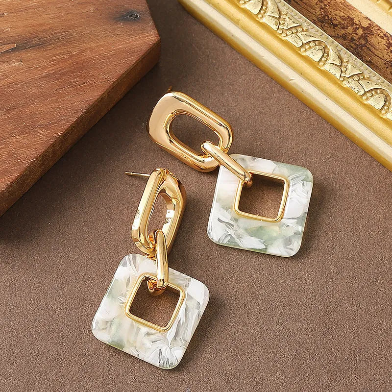 Pair of hollow geometric square earrings with chamfered pattern in silver or black electroplated finish.