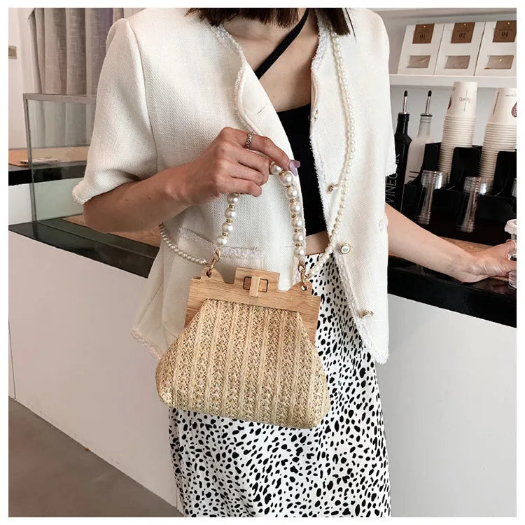 Beige woven straw women's shoulder bag with pearl chain detail, showing interior zipper pockets.