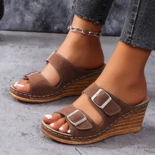 Women's creamy-white beach slippers with a decorative wedge buckle on the strap.