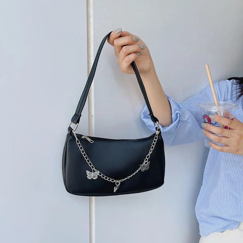 Square black PU leather crossbody bag with a butterfly chain strap and external structured pocket.