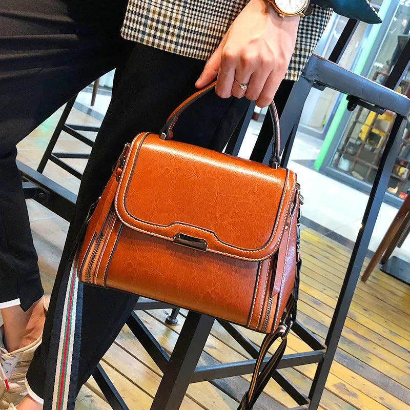Women's brown genuine oil wax leather messenger bag showing front view with double straps and visible sewing details.