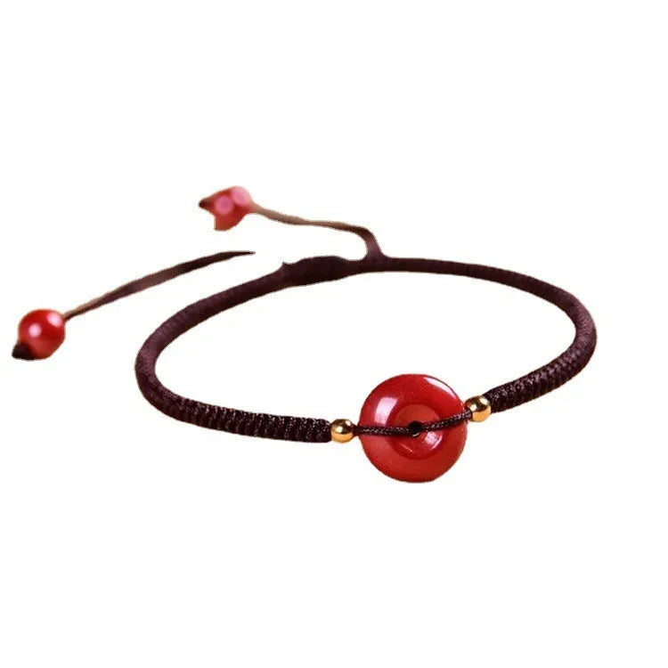 Heart-shaped cinnabar bead on an adjustable knot rope bracelet with a decorative peace buckle closure.