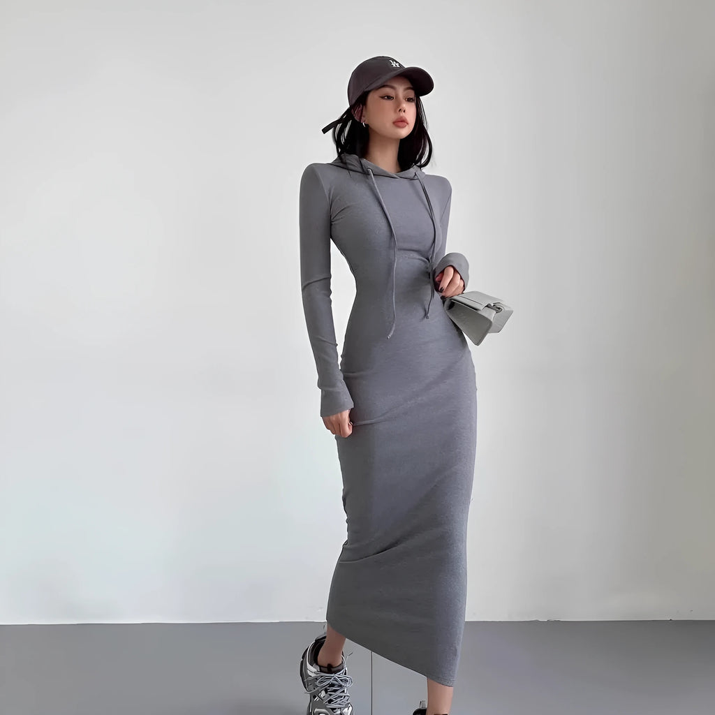 A woman wearing a grey high-waist hooded long sleeve sheath dress, knee-length pullover style.