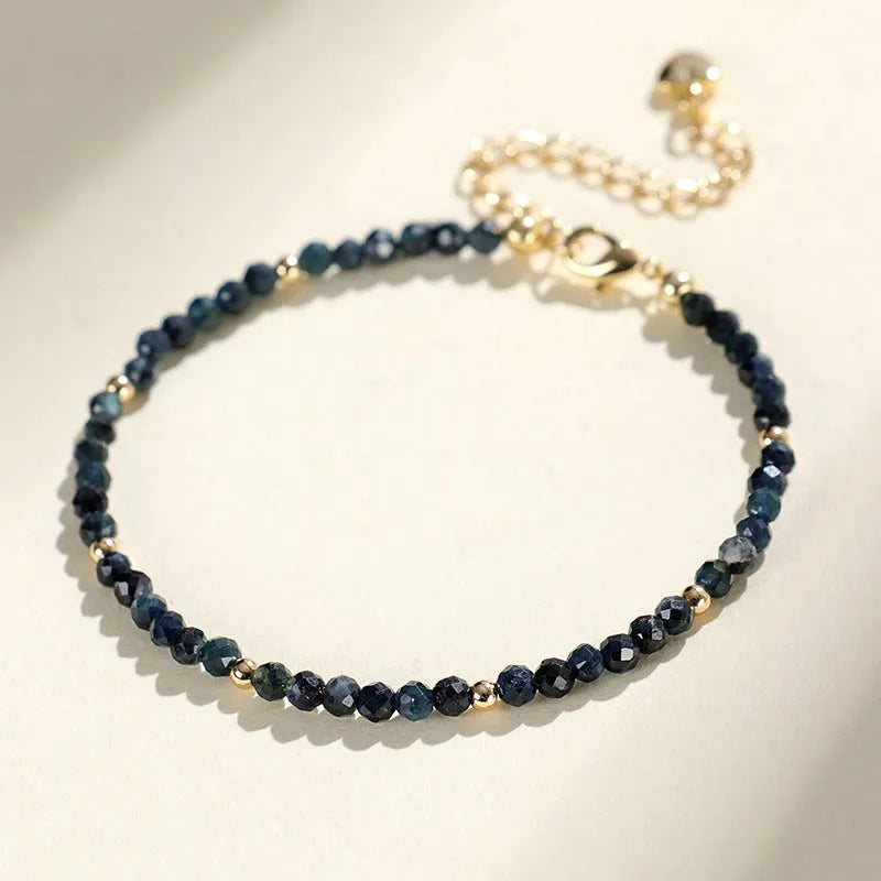 3mm blue tourmaline cut bead bracelet with spacer beads on a wrist