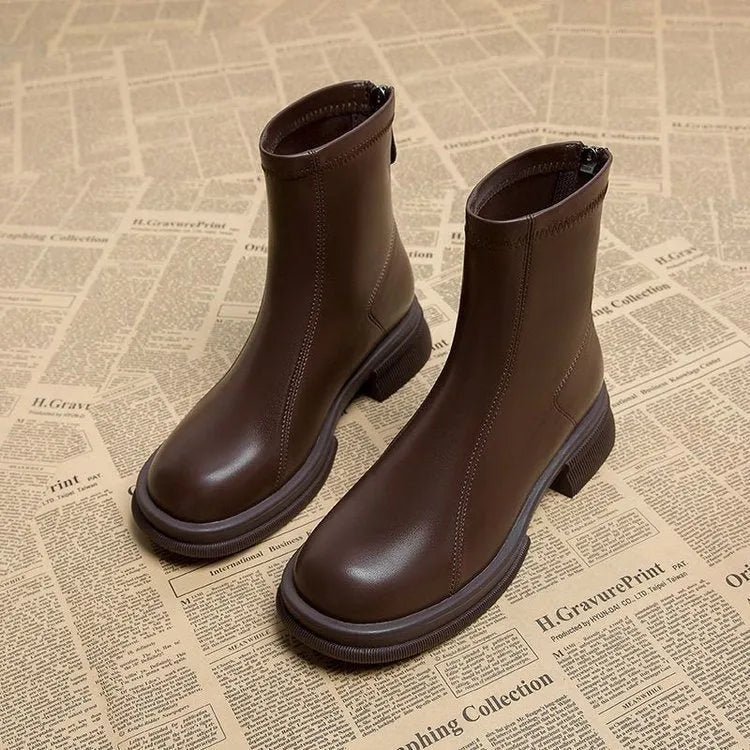 Women's black flat heel ankle boots with a back zipper and round toe, shown on a foot.