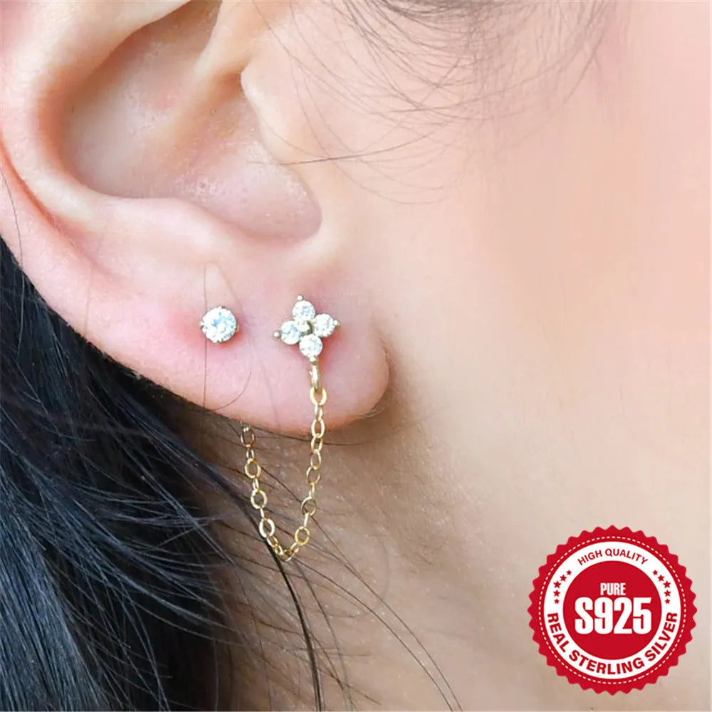Close-up of a women's S925 sterling silver stud earring with a diamond flower, chain, and tassel design in a gold colour.