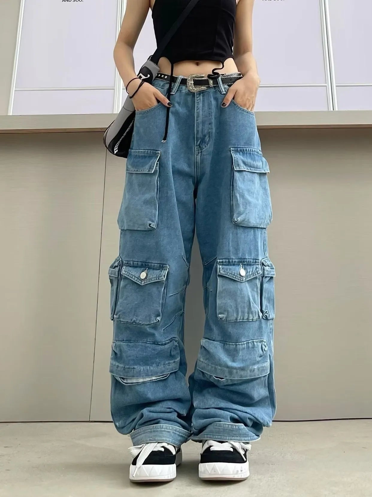 Blue tie-dyed high waist wide leg denim trousers on a woman, showing multiple pockets and street hipster style.