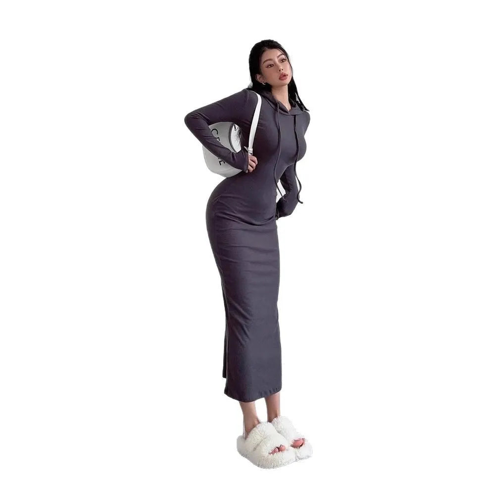 A woman wearing a grey high-waist hooded long sleeve sheath dress, knee-length pullover style.