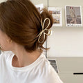 A silver and a gold alloy hair barrette with a prominent bow design.