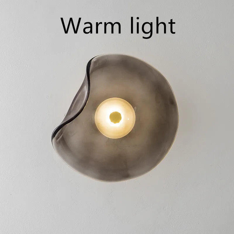 Round glass wall lamp in a choice of colours for bedroom bedside lighting.