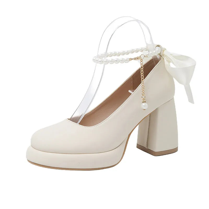 Beige women's Mary Jane shoes with a chunky heel, round toe, and ankle strap with a pearl and buckle.
