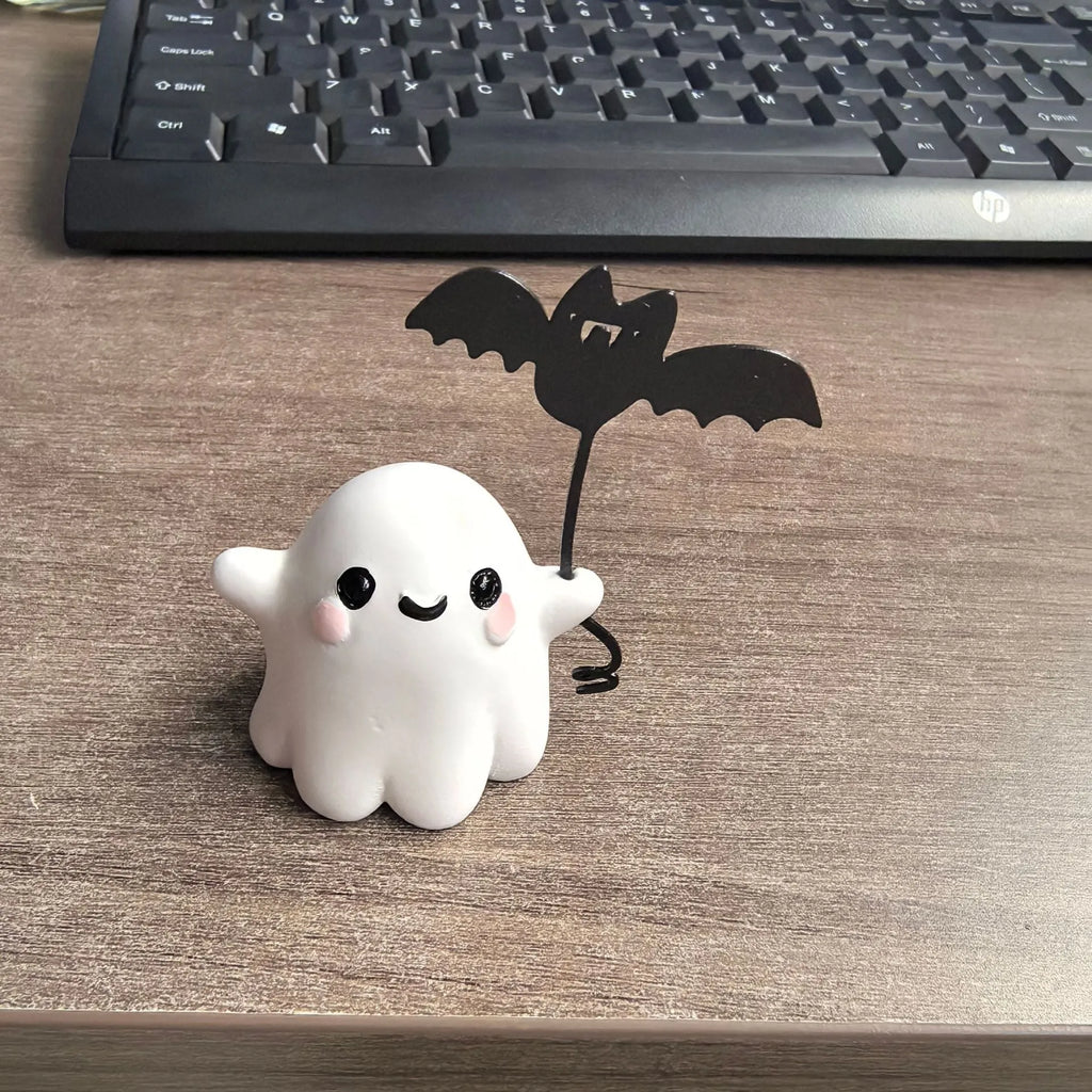 Small resin statue of a ghost holding a bat while walking a dog, a Halloween decoration.