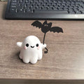 Small resin statue of a ghost holding a bat while walking a dog, a Halloween decoration.