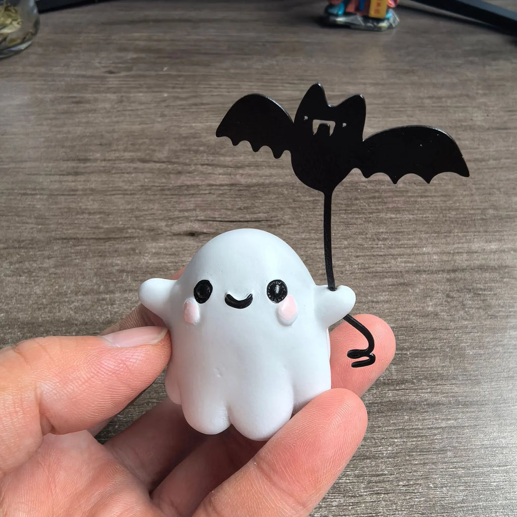 Small resin statue of a ghost holding a bat while walking a dog, a Halloween decoration.