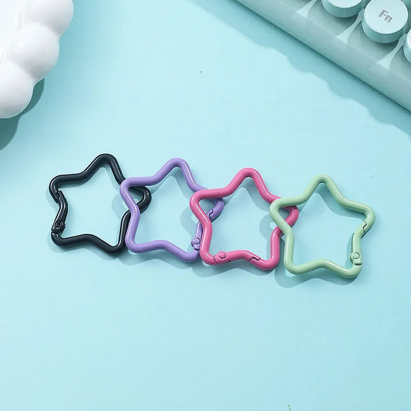 Zinc alloy five-pointed star keychain in light pink colour on a black background.