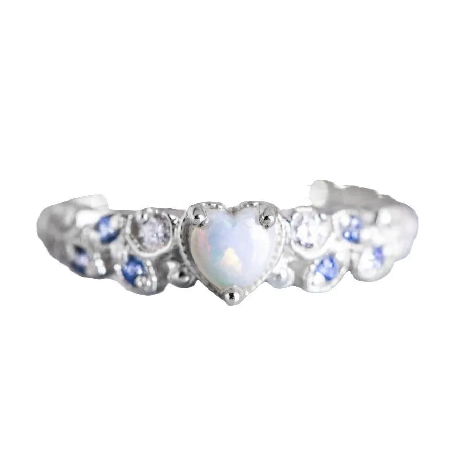 White alloy women's heart ring with floral opal ocean love design on a finger.