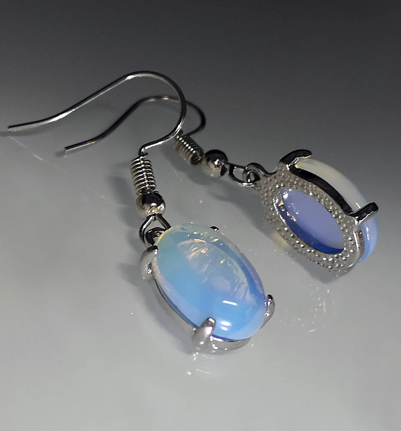 A pair of retro-style drop earrings with a moonlight opal colour and simple cross detail.