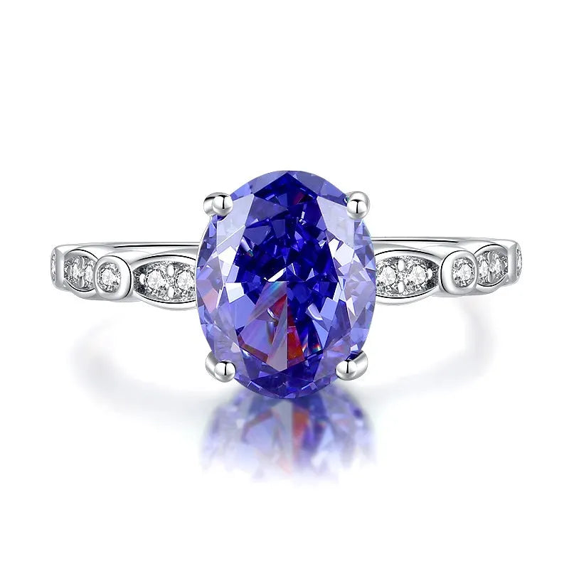 Women's heart-shaped sterling silver ring with ice flower cut coloured zircon stone on finger.