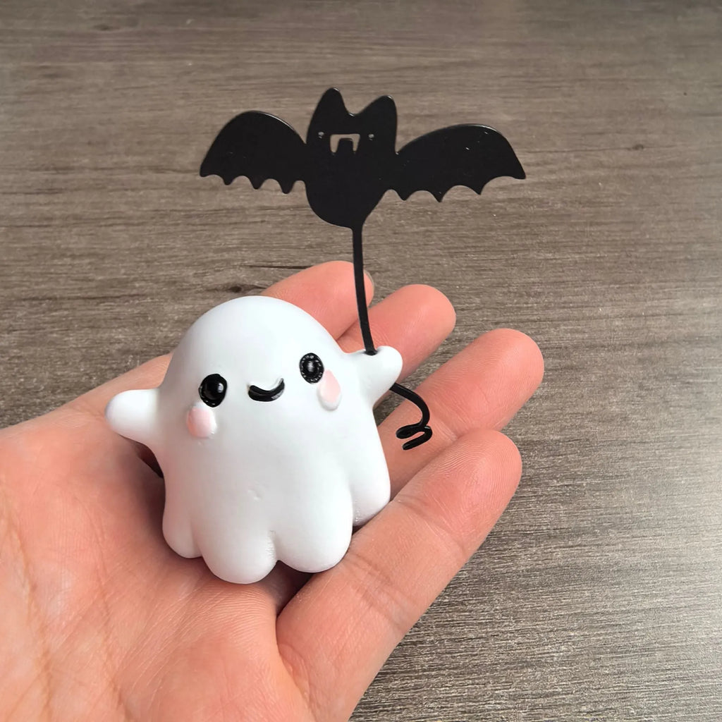 Small resin statue of a ghost holding a bat while walking a dog, a Halloween decoration.