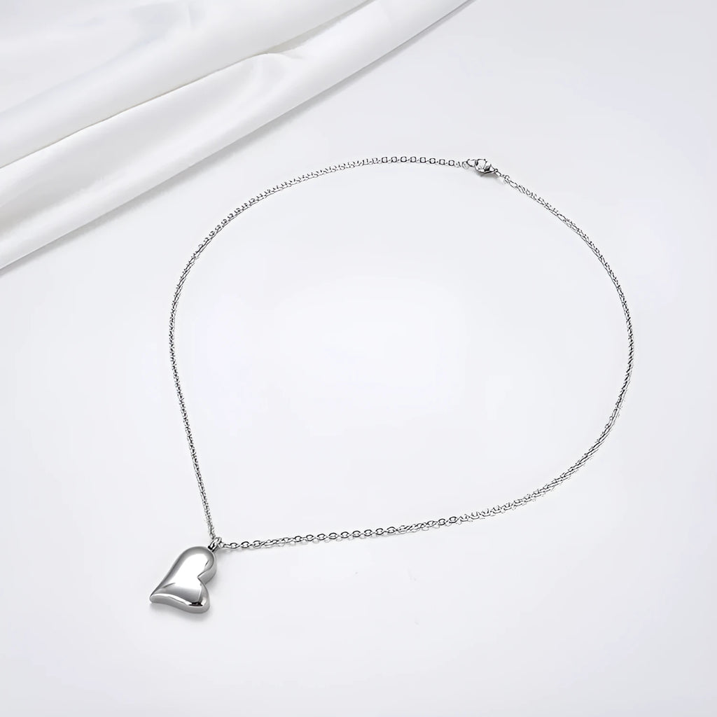 Silver curved peach heart stainless steel pendant necklace on a model, showing the adjustable chain length.