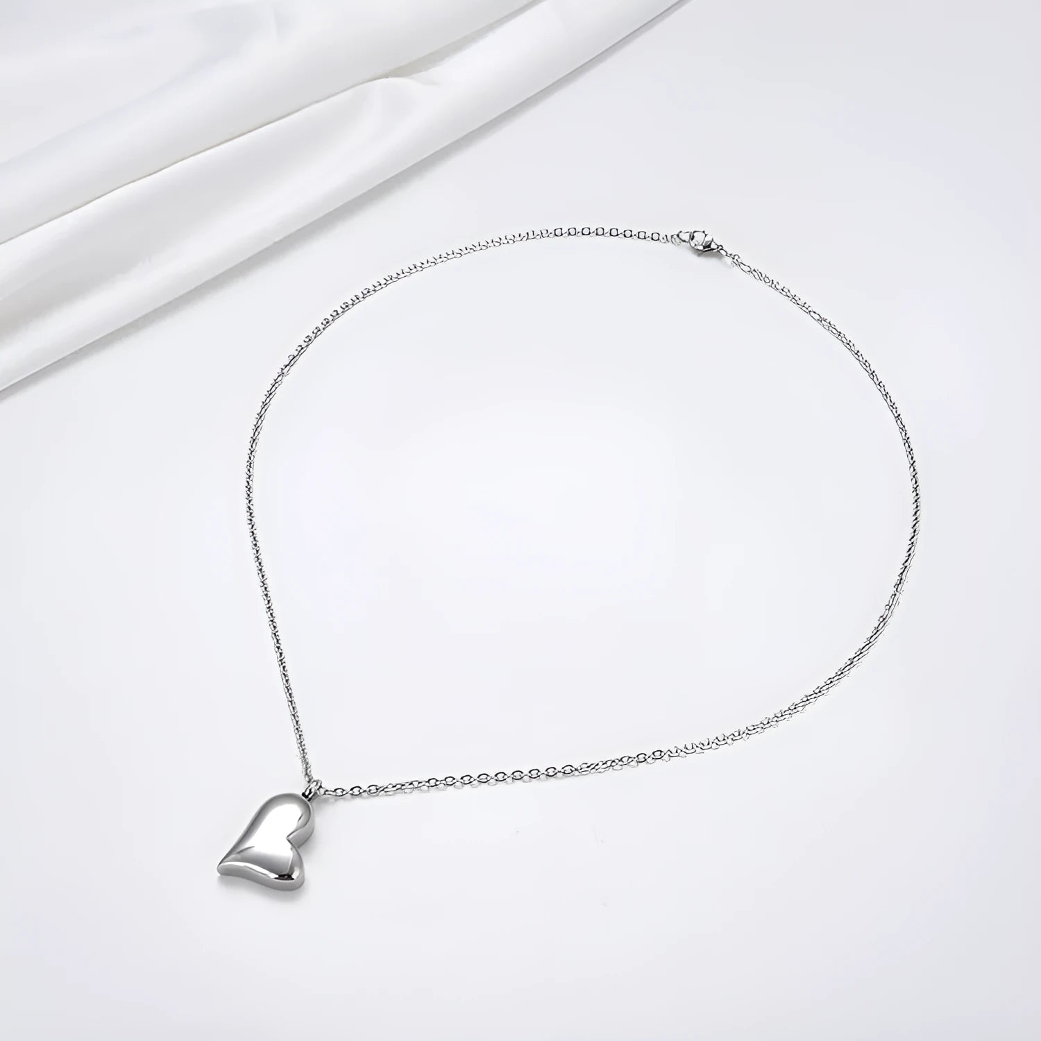Silver curved peach heart stainless steel pendant necklace on a model, showing the adjustable chain length.