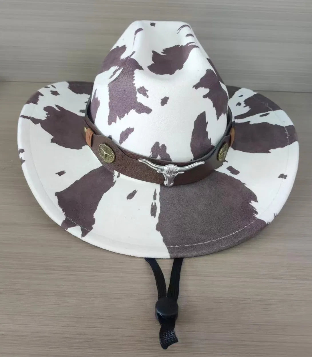 Brown leather velvet curved edge Western cowboy hat with a conical crown on a table.