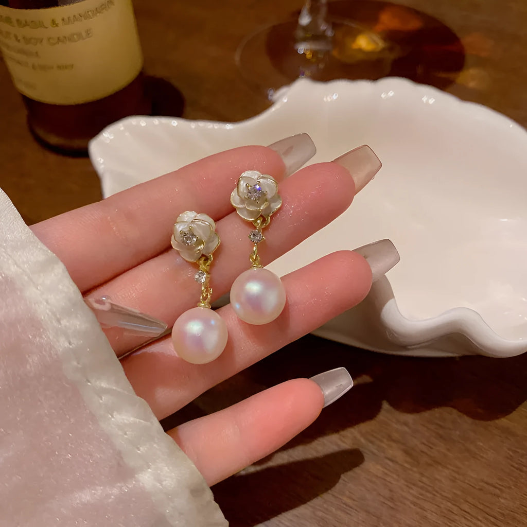 A pair of camellia flower-shaped alloy stud earrings for women on a white background.