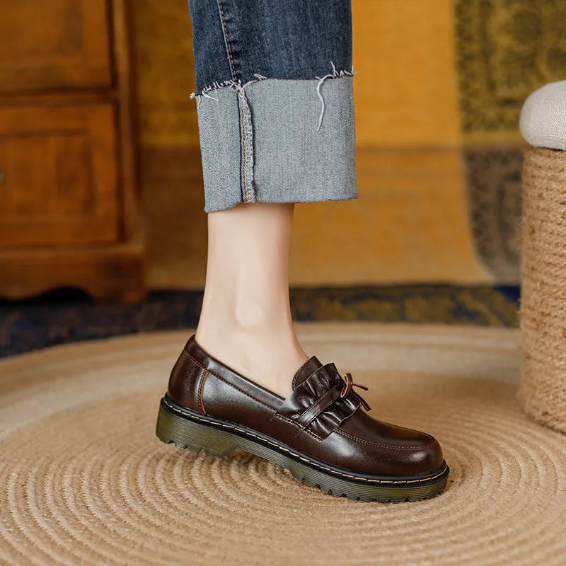 Women's black leather chunky heel shoes with a round toe on a neutral background.