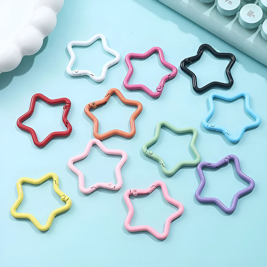 Zinc alloy five-pointed star keychain in light pink colour on a black background.