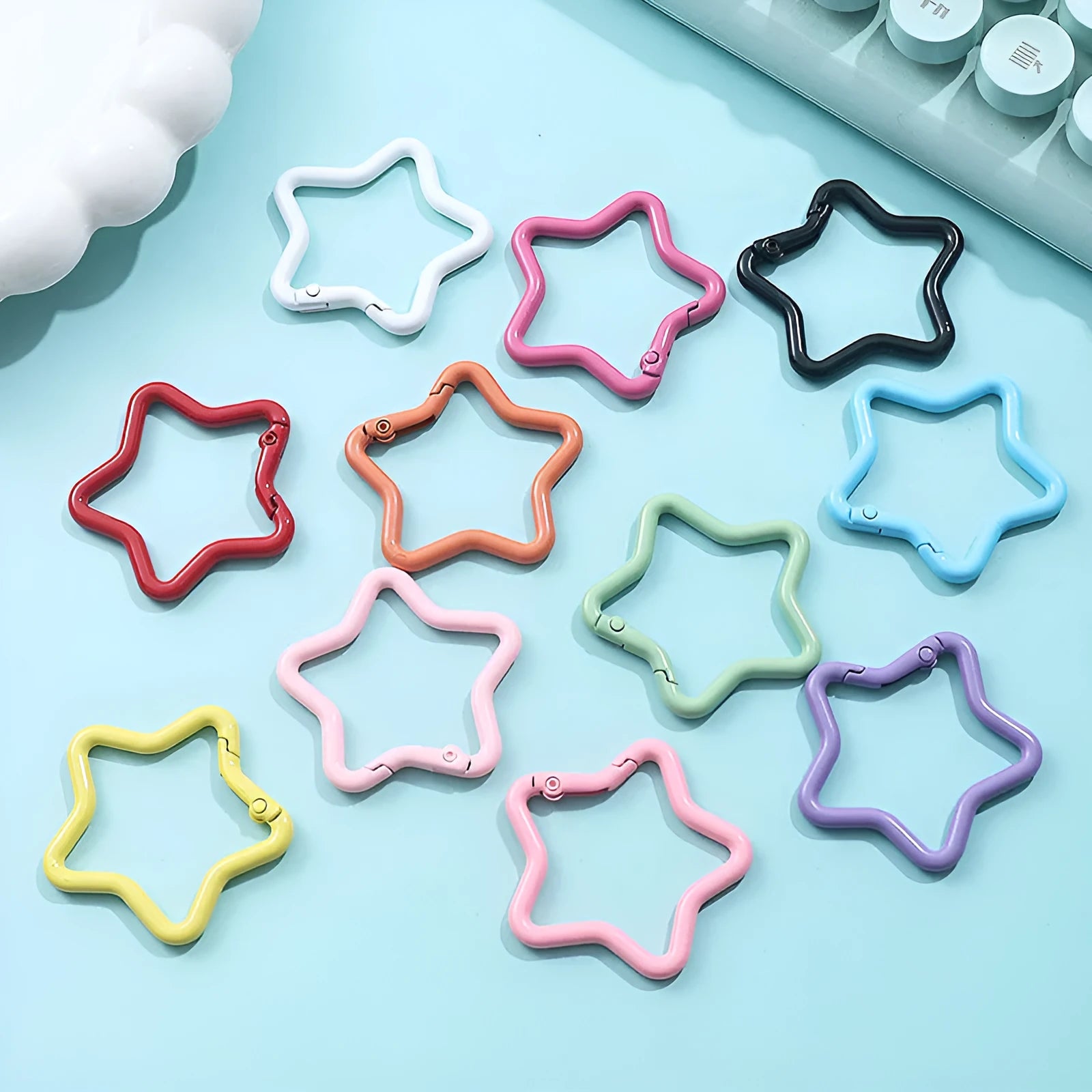 Zinc alloy five-pointed star keychain in light pink colour on a black background.