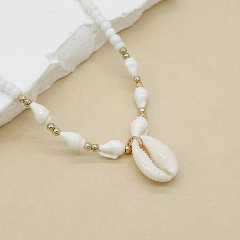 White conch shell pendant necklace on a regular chain, made from mother pearl shellfish.