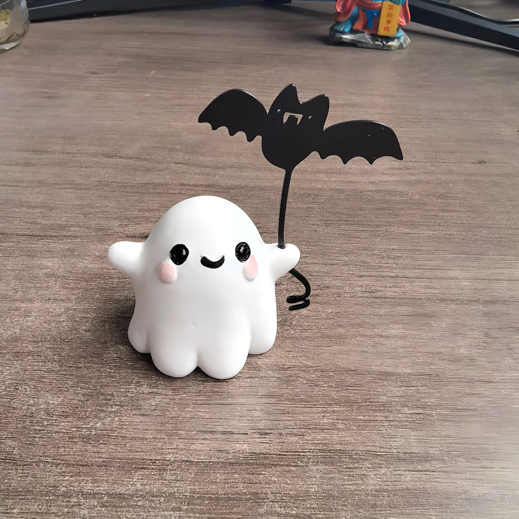 Small resin statue of a ghost holding a bat while walking a dog, a Halloween decoration.